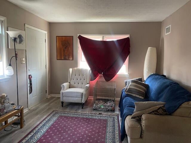 sitting room with visible vents, a healthy amount of sunlight, baseboards, and wood finished floors