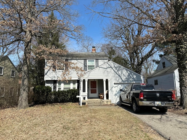 view of front of property with aphalt driveway, an attached garage, and a chimney