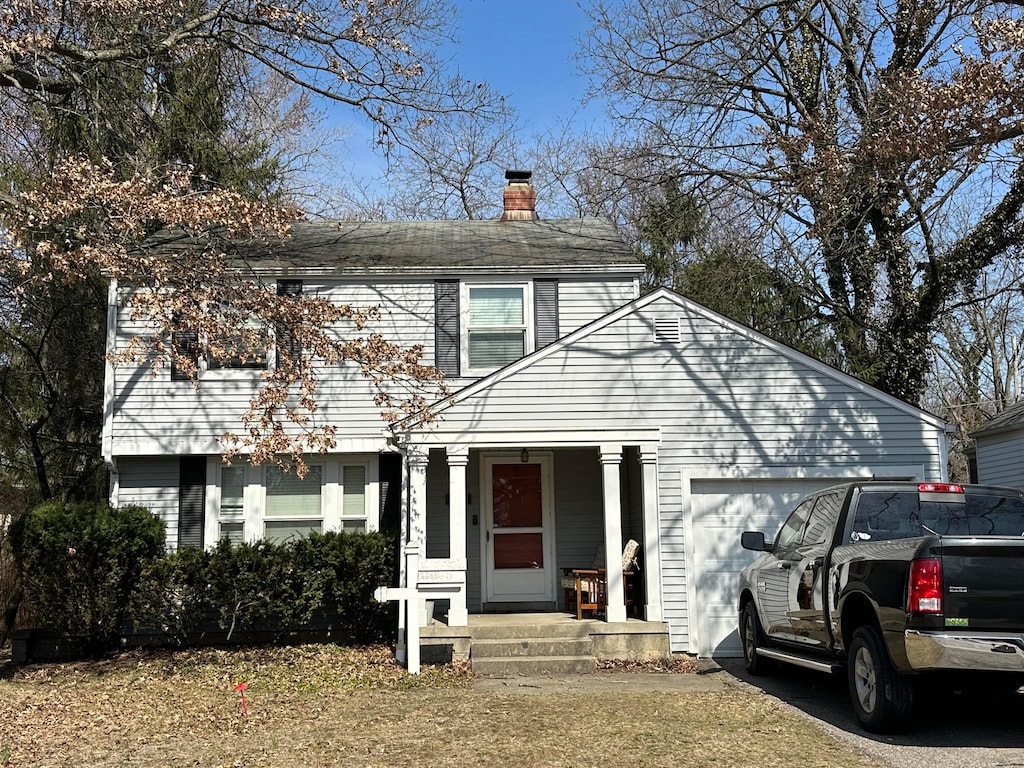 view of front of home featuring aphalt driveway, a chimney, an attached garage, and a shingled roof