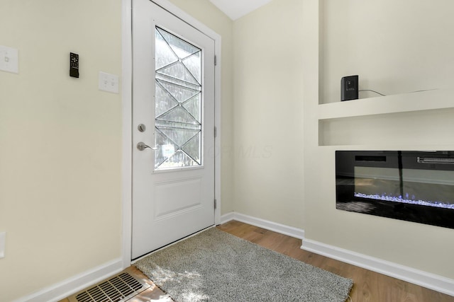 doorway to outside with visible vents, plenty of natural light, baseboards, and wood finished floors