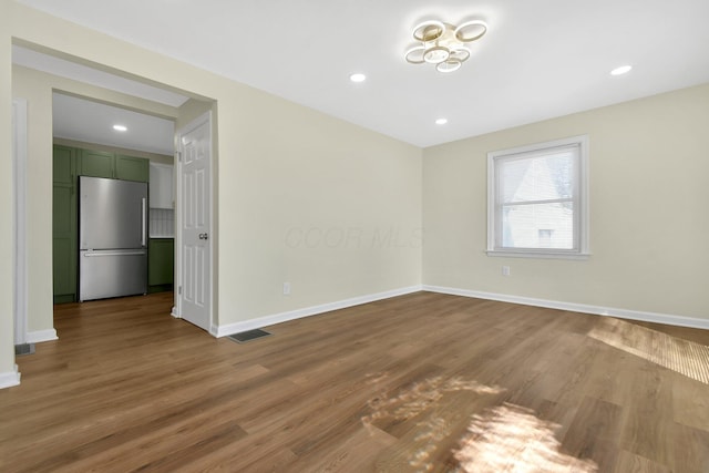 empty room with visible vents, recessed lighting, baseboards, and wood finished floors