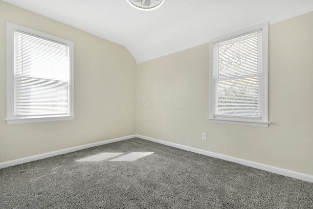 carpeted spare room with baseboards and lofted ceiling