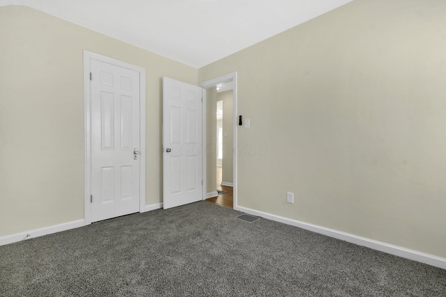 unfurnished bedroom featuring visible vents, baseboards, and dark colored carpet