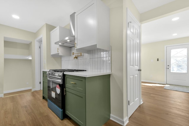 kitchen with light wood-type flooring, stainless steel range with gas cooktop, green cabinets, and light countertops