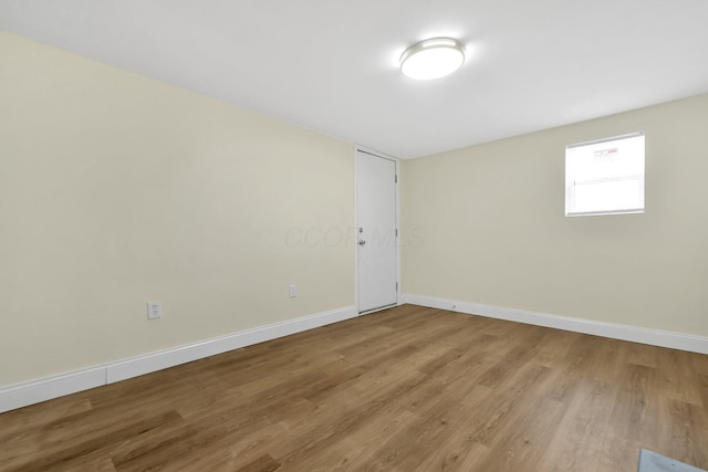 spare room with baseboards and wood finished floors