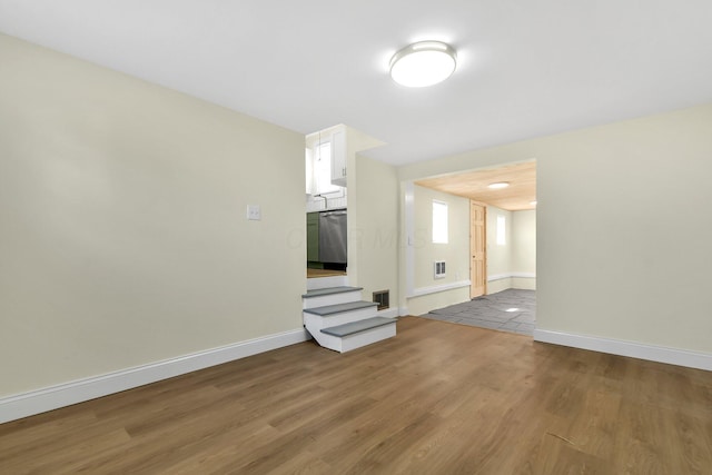 unfurnished room with wood finished floors, visible vents, and baseboards