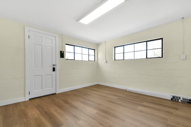 empty room featuring light wood-type flooring, baseboards, and concrete block wall