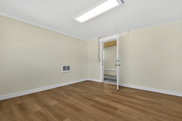 spare room featuring crown molding, wood finished floors, visible vents, and baseboards