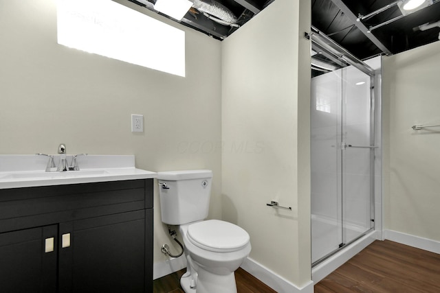 bathroom with vanity, wood finished floors, baseboards, a shower stall, and toilet