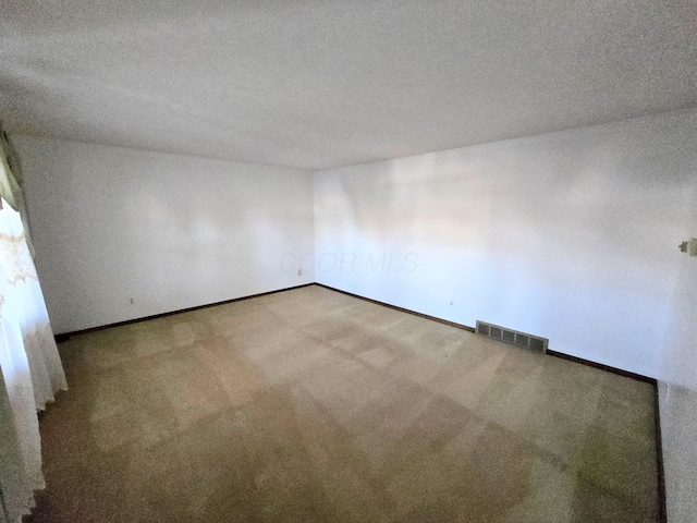 carpeted empty room featuring visible vents, baseboards, and a textured ceiling