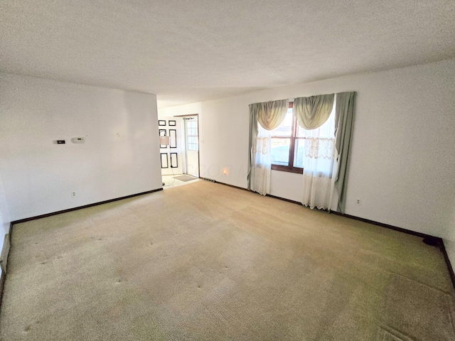 carpeted empty room featuring baseboards and a textured ceiling