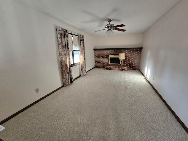 unfurnished living room featuring light colored carpet, a fireplace, baseboards, and a ceiling fan