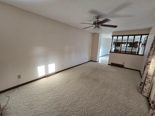 carpeted empty room featuring visible vents, baseboards, and ceiling fan