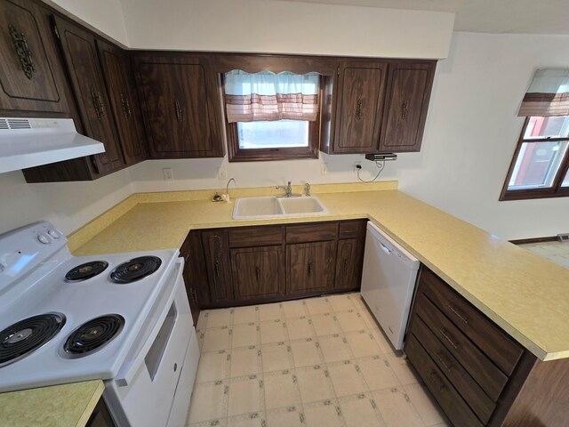 kitchen with under cabinet range hood, light floors, a peninsula, white appliances, and a sink