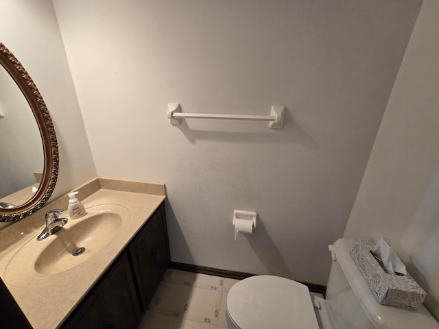 bathroom featuring toilet, vanity, and baseboards