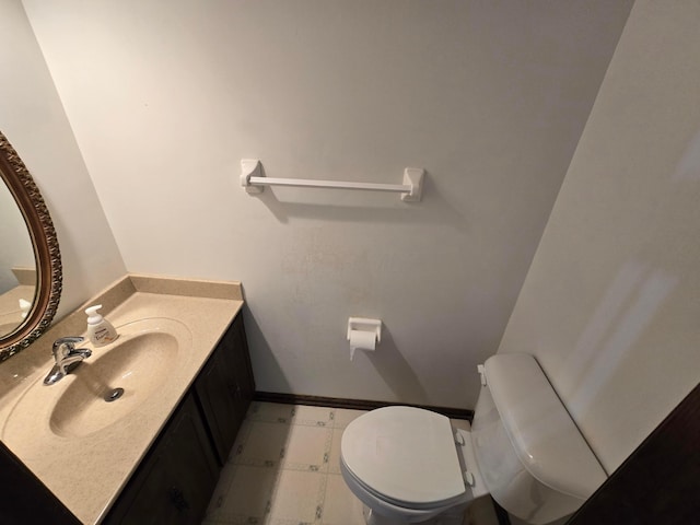 half bathroom with toilet, vanity, and baseboards