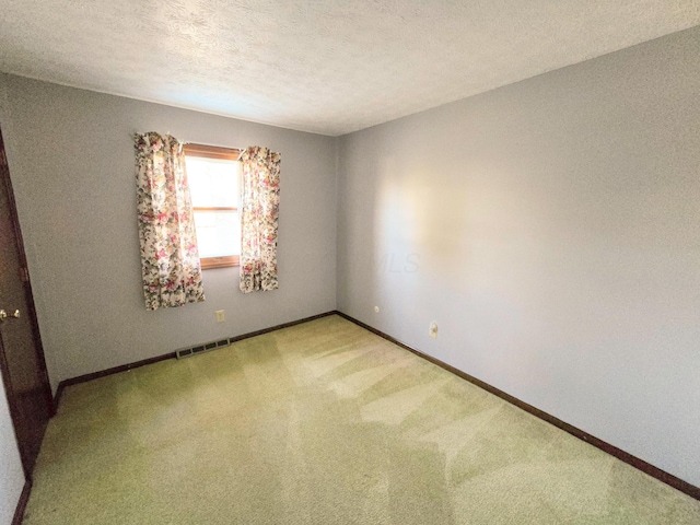 unfurnished room featuring baseboards, visible vents, a textured ceiling, and carpet