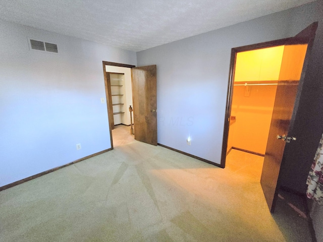 unfurnished bedroom featuring visible vents, baseboards, a textured ceiling, and a spacious closet