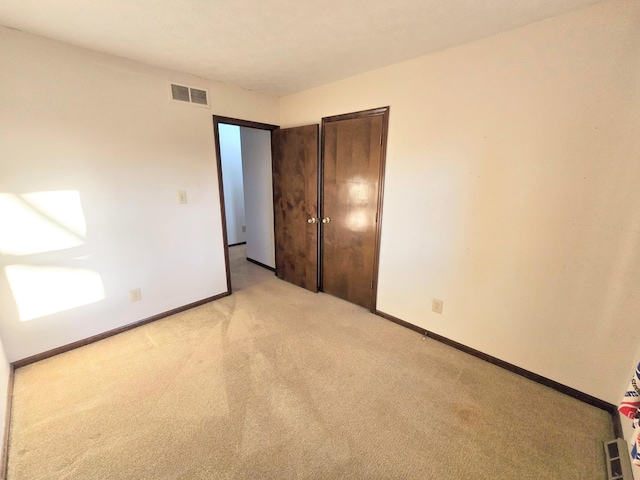 unfurnished bedroom featuring light carpet, visible vents, a closet, and baseboards