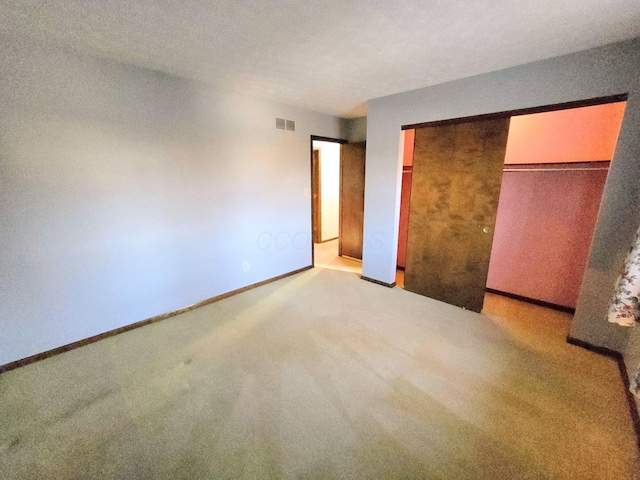 unfurnished bedroom with light carpet, visible vents, a closet, and baseboards