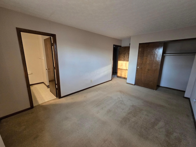 unfurnished bedroom with connected bathroom, baseboards, carpet flooring, a closet, and a textured ceiling