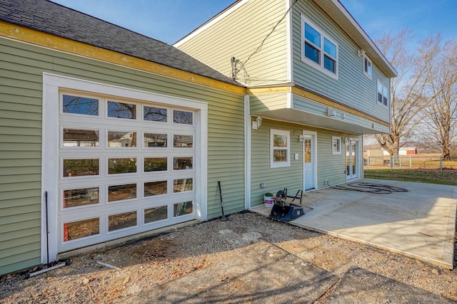 rear view of house featuring driveway, a patio, and an attached garage