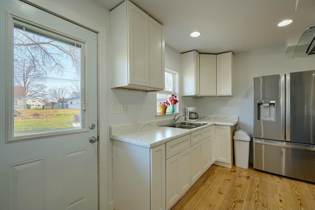 kitchen featuring a sink, light wood-type flooring, white cabinets, and stainless steel fridge with ice dispenser