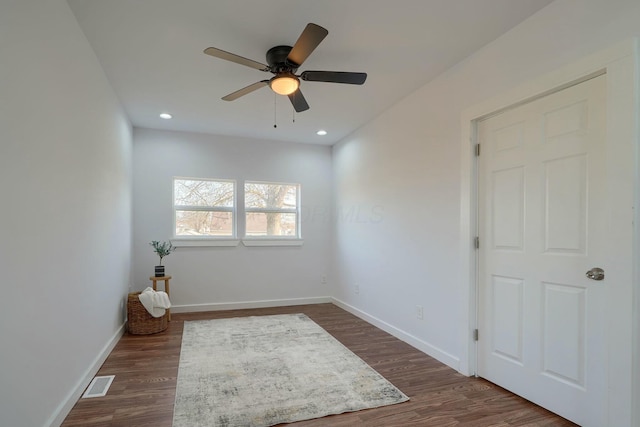 empty room with visible vents, baseboards, dark wood-type flooring, and a ceiling fan