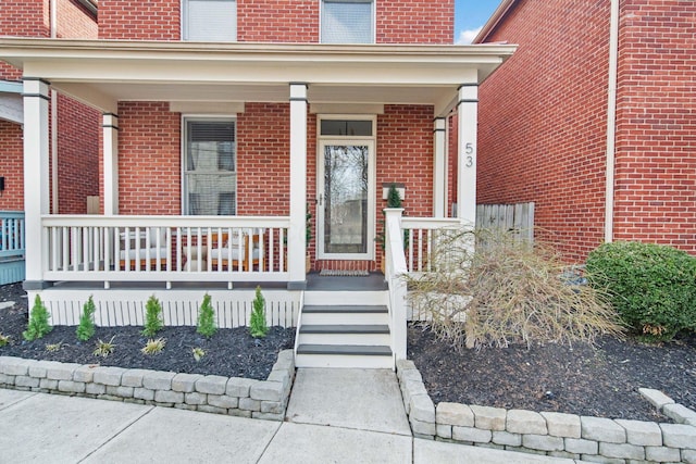 view of exterior entry with brick siding and covered porch