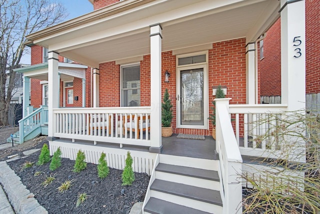 doorway to property with brick siding and covered porch