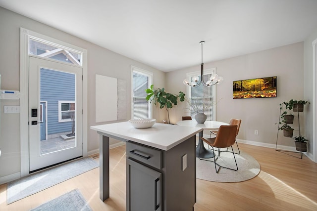 kitchen featuring a notable chandelier, gray cabinetry, a center island, light wood-style floors, and light countertops