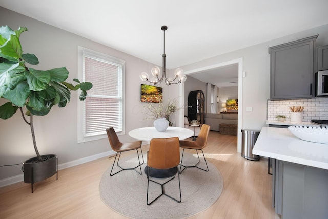 dining room featuring baseboards, light wood finished floors, and a chandelier