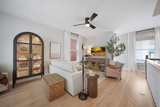 living room featuring baseboards, light wood-style floors, and a ceiling fan