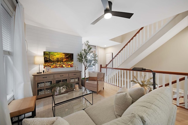 living area featuring stairs, ceiling fan, and wood finished floors