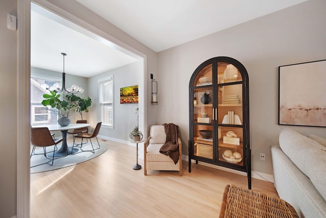 living area with wood finished floors, baseboards, and a chandelier