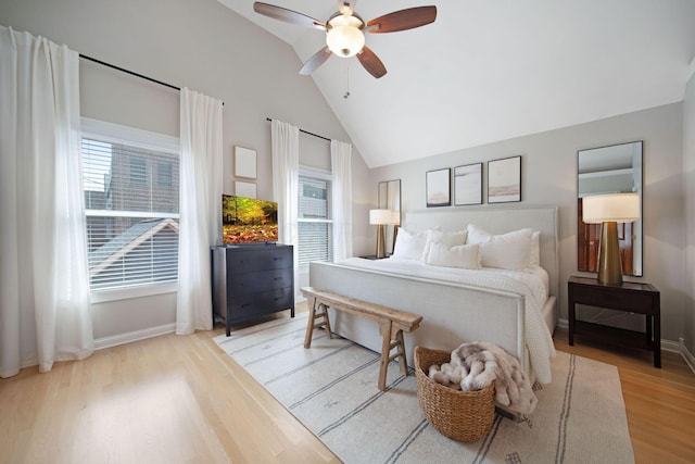 bedroom featuring multiple windows, baseboards, lofted ceiling, and wood finished floors