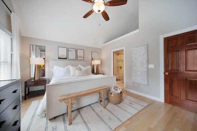 bedroom with a ceiling fan, baseboards, ensuite bath, lofted ceiling, and light wood-style flooring