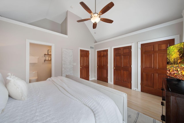 bedroom featuring a ceiling fan, wood finished floors, high vaulted ceiling, ensuite bath, and multiple closets