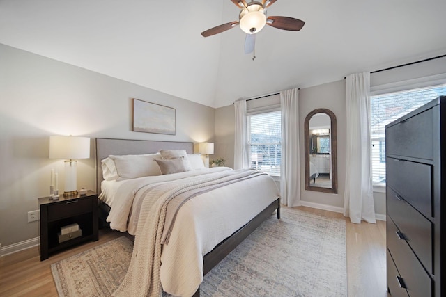 bedroom featuring light wood-type flooring, baseboards, a ceiling fan, and vaulted ceiling