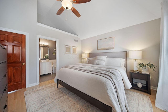 bedroom with visible vents, connected bathroom, vaulted ceiling, wood finished floors, and a ceiling fan