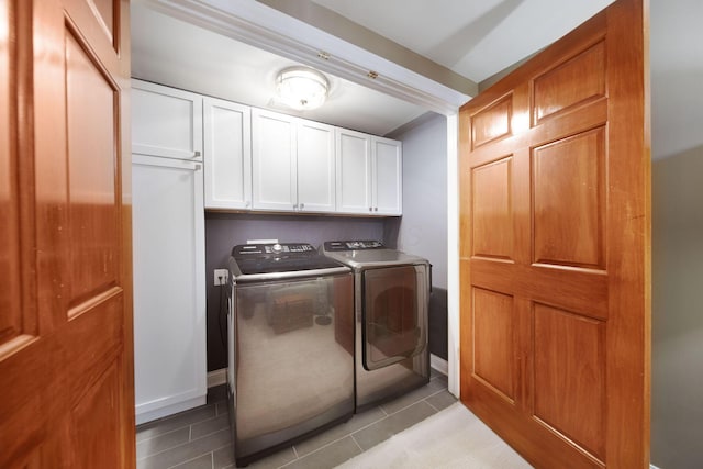 laundry room featuring baseboards, cabinet space, washing machine and dryer, and light tile patterned flooring