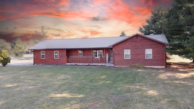 cabin with a yard, a porch, faux log siding, and metal roof