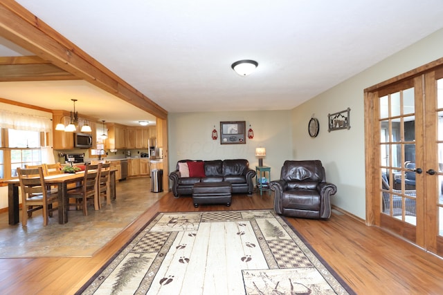 living area with a notable chandelier, french doors, light wood-type flooring, and baseboards