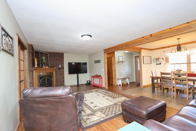 living room with a fireplace, baseboards, an inviting chandelier, and wood finished floors