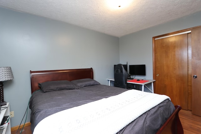 bedroom with a closet, a textured ceiling, and wood finished floors