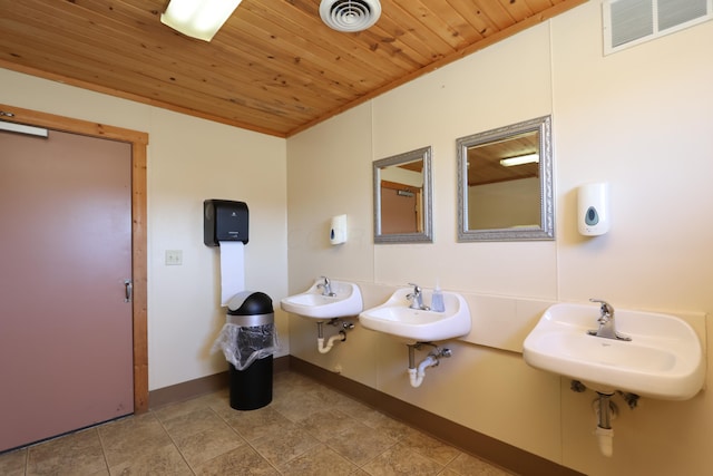 bathroom with wood ceiling, visible vents, two sinks, and baseboards