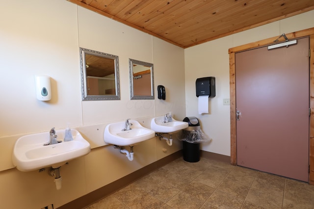 bathroom featuring baseboards, wood ceiling, and two sinks