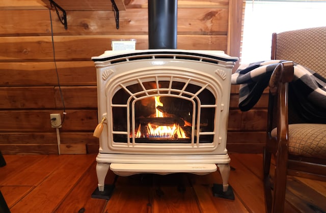 room details featuring wooden walls, wood finished floors, and a wood stove