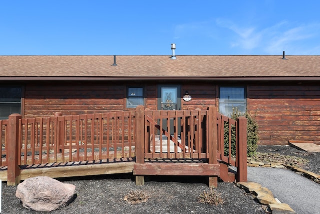 exterior space featuring roof with shingles and a wooden deck