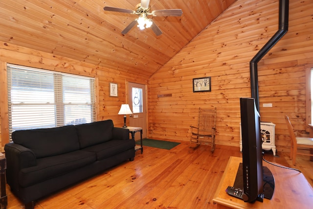 living area featuring a ceiling fan, vaulted ceiling, wood ceiling, wood walls, and light wood-type flooring